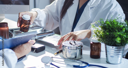 Medical team having a meeting with doctors in white lab coats and surgical scrubs seated at a table discussing a patients working online using computers in the medical industry.