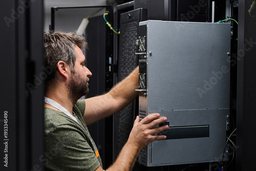 IT technician installing server hardware in a data center during routine maintenance and system upgrade