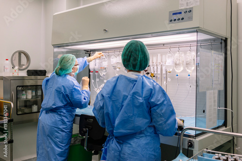 Pharmacists preparing IV medications in sterile pharmacy hood