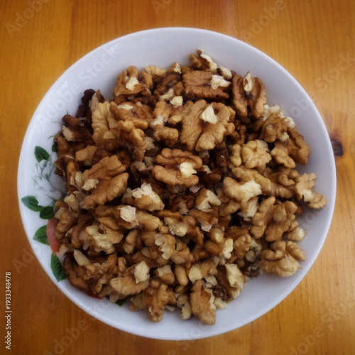 Shelled walnut kernels in a white bowl on a wooden table