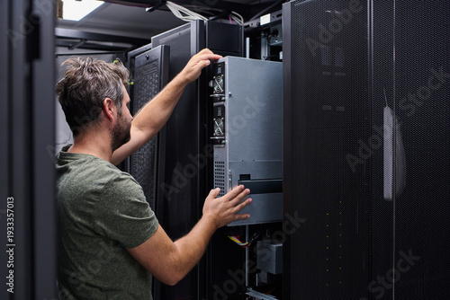 IT technician installing and maintaining servers in a data center rack for network infrastructure