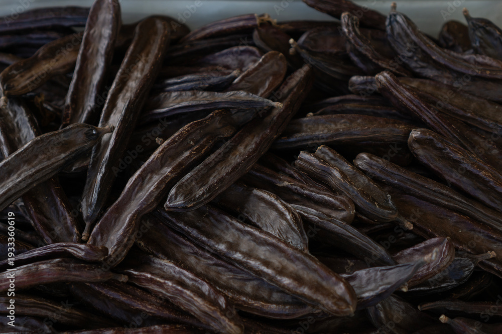 Fototapeta premium carob pods market background dark brown textured surface traditional mediterranean dried fruits at lamezia terme italian street fair concept of food industry, agriculture, commerce