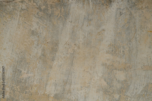 Close-up of a weathered plastered wall with peeling and flaking paint in shades of beige, grey and ochre yellow, showing signs of age and decay