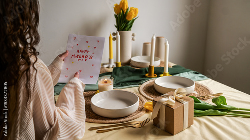 Foto Woman holding a handmade Mother's Day card at a beautifully set table with tulip