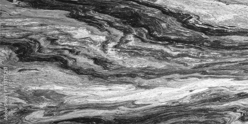 An abstract black and white landscape captures the motion of a flowing waterfall cascading over dark rocks and stones with a textured wave of white water