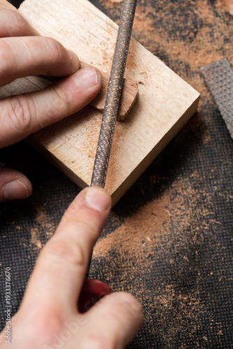 The craftsman sharpens a wooden workpiece with a file