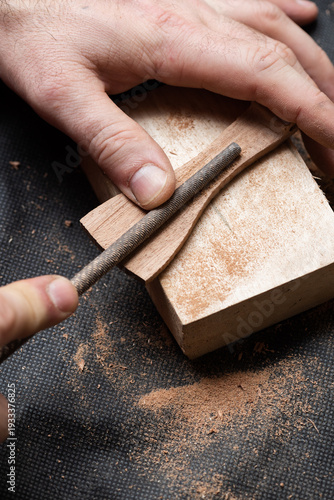 A craftsman sharpens a wooden workpiece with a file