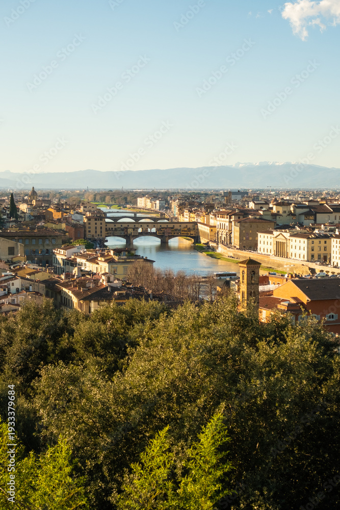 Obraz premium View of Florence city with bridges and buildings along the river at midday in Italy