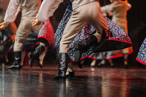 Latvian folk dancers in traditional costumes performing on stage, showcasing intricate patterns and vibrant colors in a cultural celebration