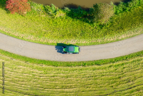 High angle drone shot of a car driving on a winding asphalt road built on a d...