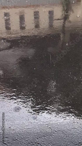Rainy day scene with water on the ground and building reflection.