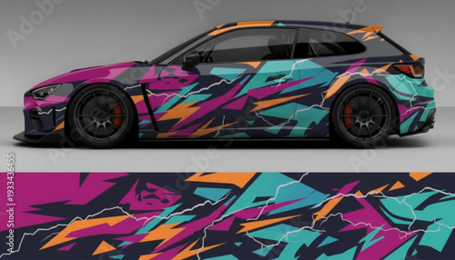 A dark grey hatchback car with a vibrant, abstract graphic wrap featuring magenta, orange, and teal geometric shapes and lightning bolts.