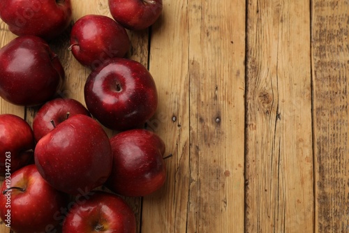 Fresh ripe red apples on wooden table, flat lay. Space for text