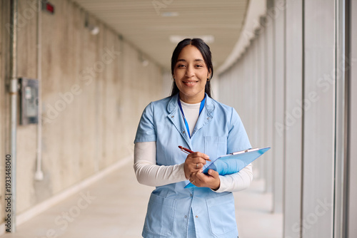 Photos Happy nurse working at doctor's office and looking at camera.