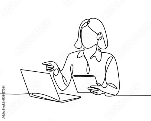 A woman sits at a desk with a laptop and tablet, engaged in a productive work session.
