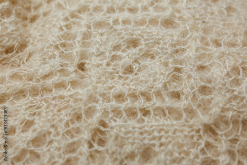 Beige wool knit fabric with airy openwork stitches and handmade lace texture