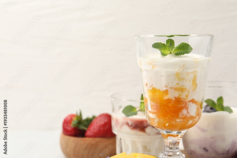 Fototapeta premium Tasty yogurt with mango and mint on white table, closeup. Space for text