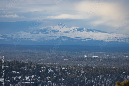 A mountain range is visible in the distance, with snow covering the peaks. The sky is cloudy, and the mountains are in the background