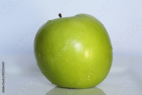 A green apple with water drops on it.