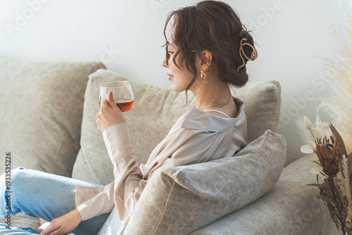 Tableau sur toile A stylish Asian woman sitting on a sofa and drinking tea