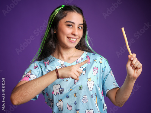 Slika na platnu A smiling woman dentist pointing to an ancestral toothbrush Miswak