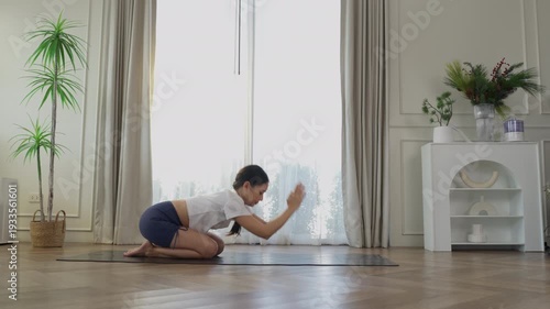 Young Asian woman practicing camel yoga pose variation on mat at home, stretching body for flexibility wellness mindfulness workout