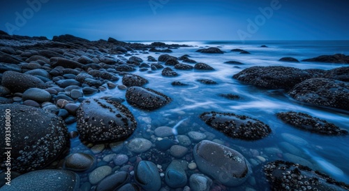 Coastal rocks meet ocean waters under a dusky sky at dusk or dawn