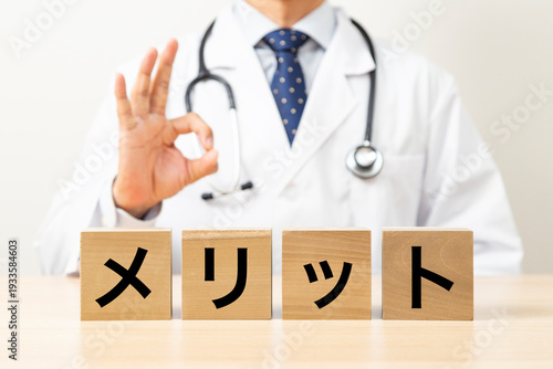 「メリット」と書かれたブロックとOKサインをする医師