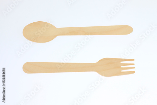 Simple wooden spoon and fork lie against a clean white background. They appear fresh, unbroken, and unused. Minimalist design emphasizes natural wood texture and smooth edges. good for home cooking