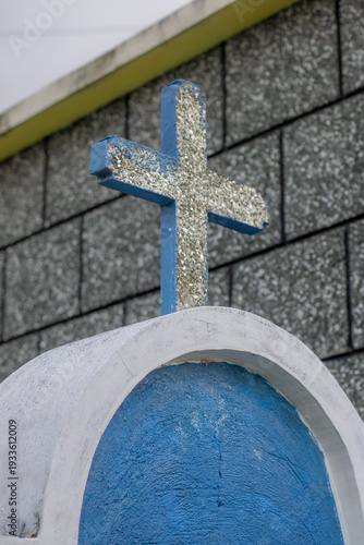 Cross on a blue dome in a church setting with gray tiles under a clear sky