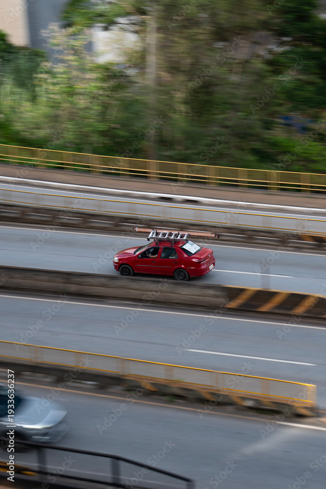 Fototapeta premium Red Fiat Siena side profile in motion, Compact work sedan driving on city avenue