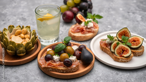 Appetizers with cocktails. Artichoke canned, olives, bruschetta with italian prosciutto cotto, crudo and figs, cheese, grape. Grey  stone surface. Vertical image.