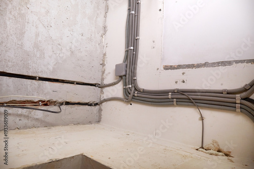 The electrical wires in the protective corrugated cable tube and the junction box are neatly laid on the ceiling. Installation of electrical wiring in the repaired room.