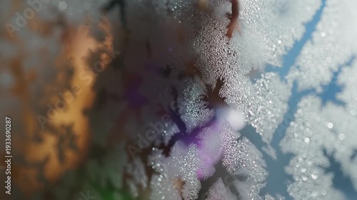 Beautiful macro shot of intricate ice crystals forming on a cold window pane with soft morning light filtering through the glass.