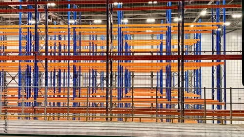 Foto Interior of a large industrial warehouse with blue high-capacity storage racks, green plastic crates on wooden pallets and a stepladder
