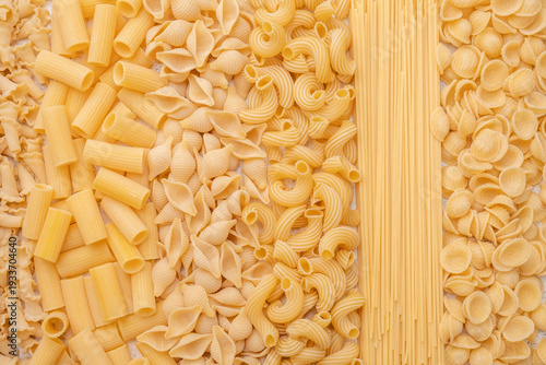 Variety of pasta shapes arranged on a flat surface before cooking or serving