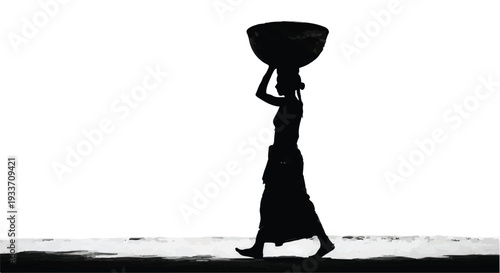 Silhouette of a woman carrying a basket on her head walking along a beach