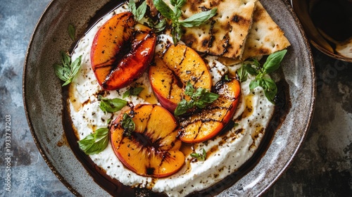 A plate of creamy burrata cheese topped with grilled peaches and fresh basil leaves