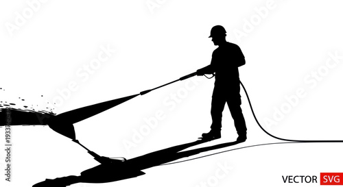 Silhouette of worker pressure washing, creating spray and shadow