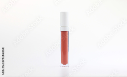 Transparent lip gloss tube with coral liquid lipstick and white cap isolated on white background. Minimalist cosmetic packaging mockup for beauty branding, makeup advertising, skincare marketing