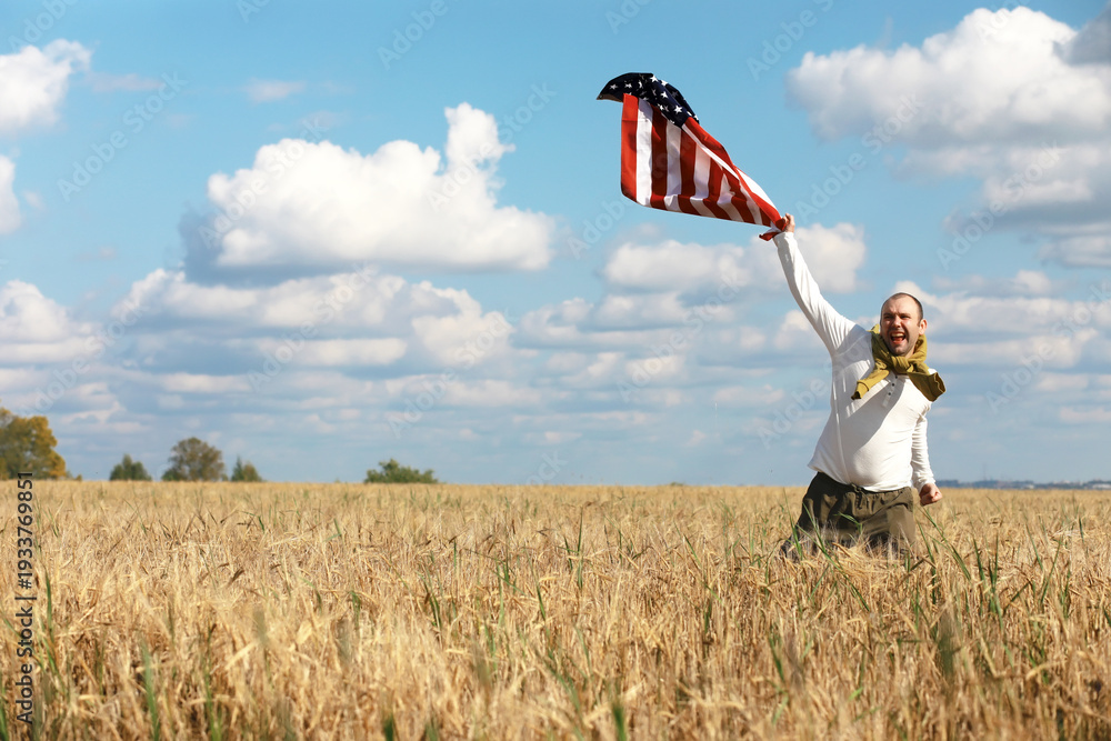 Fototapeta premium Man waving American flag standing in grass farm agricultural field , holidays, patriotism, pride, freedom, political parties, immigrant