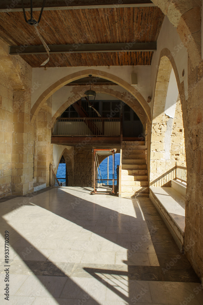 Naklejka premium A tranquil view from an ancient stone building overlooking the azure sea in the midday sun.