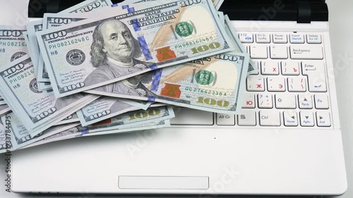 Wallpaper Mural US $100 bills slowly fall onto a computer keyboard, with business graphics in the background. Torontodigital.ca