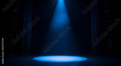 Blue spotlight illuminates an empty stage with dark curtains.
