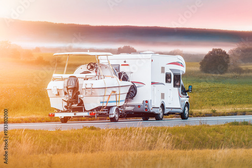 Slika na platnu Holiday motorhome carrying boat in green landscape