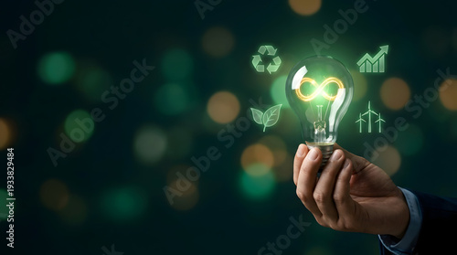 Hand holding glowing eco friendly light bulb with green infinity symbol.
