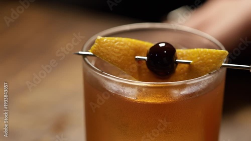 Garnishing an old fashioned cocktail with a cherry and orange peel. Old fashioned drink.