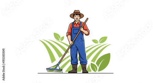 Happy young farmer wearing a hat and blue overalls stands in a green field with a rake while plants grow in the background.