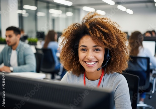 Happy African American female customer service representative with headset smiling in office, curly hair, professional workplace environment, team member at computer