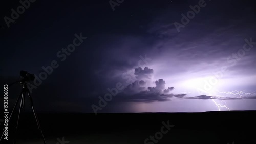 Photographer captures dramatic lightning strike over dark landscape with tripod and camera